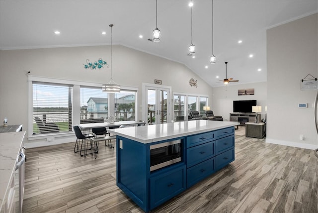 23111 Marina, Galveston, TX 77554 - kitchen featuring blue cabinets, stainless steel microwave, healthy amount of natural light, a ceiling fan, and high vaulted ceiling