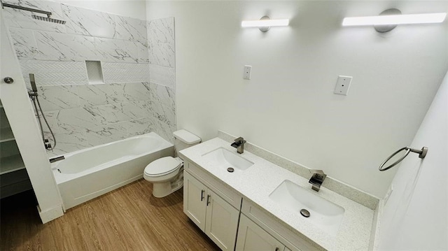 bathroom featuring double vanity, toilet, a sink, and wood finished floors