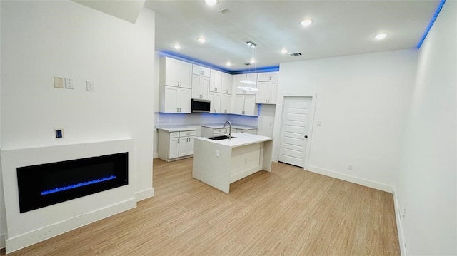 4512 Brinkley St A-B, Unit A-B Houston, TX 77051 - kitchen featuring stainless steel microwave, a sink, light wood finished floors, baseboards, and white cabinetry