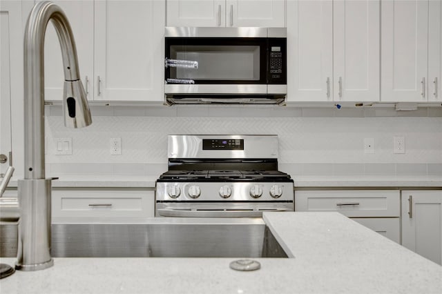 kitchen featuring light countertops, white cabinetry, appliances with stainless steel finishes, and tasteful backsplash