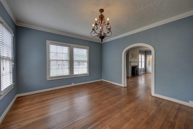 266 Monroe St, Giddings, TX 78942 - empty room with arched walkways, a chandelier, wood finished floors, baseboards, and crown molding