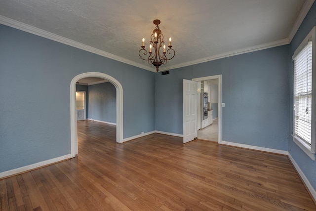 266 Monroe St, Giddings, TX 78942 - spare room with healthy amount of natural light, arched walkways, a chandelier, wood finished floors, and crown molding
