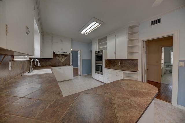 266 Monroe St, Giddings, TX 78942 - kitchen featuring open shelves, a sink, double oven, under cabinet range hood, and tasteful backsplash