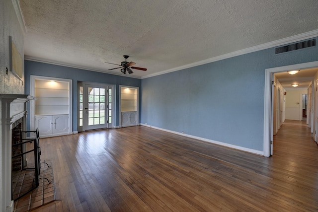 266 Monroe St, Giddings, TX 78942 - unfurnished living room featuring a textured ceiling, a ceiling fan, crown molding, a fireplace, and hardwood / wood-style floors