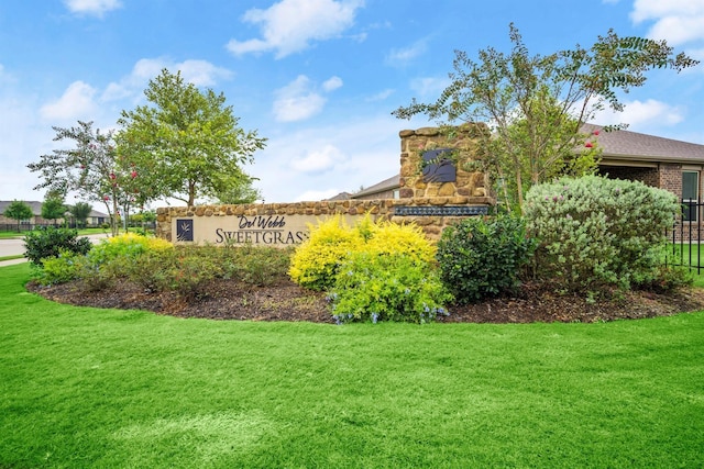 community / neighborhood sign with fence and a lawn