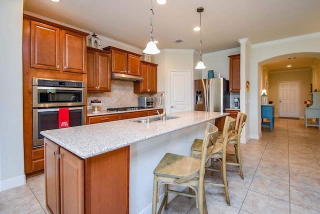 kitchen with a sink, stainless steel appliances, tasteful backsplash, crown molding, and arched walkways