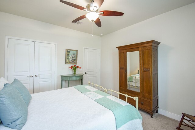 bedroom with a closet, light colored carpet, visible vents, a ceiling fan, and baseboards