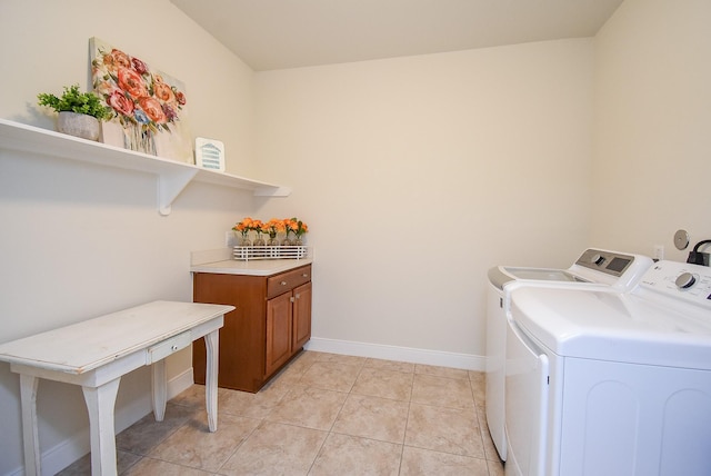 clothes washing area featuring baseboards, washer and dryer, light tile patterned flooring, and cabinet space