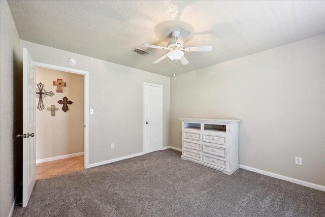 unfurnished bedroom featuring carpet flooring, a ceiling fan, visible vents, baseboards, and a textured ceiling