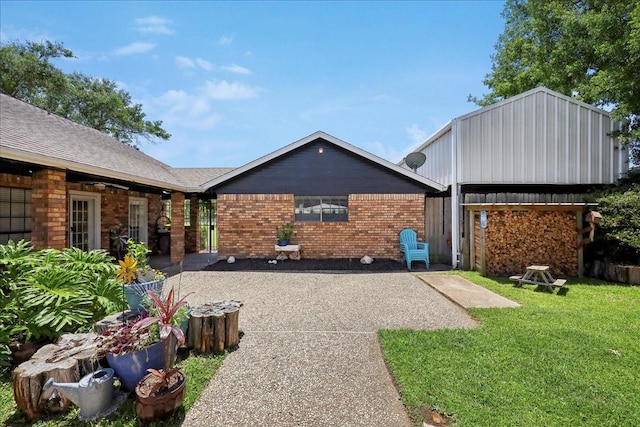 view of front of property featuring a patio area, brick siding, and a front lawn