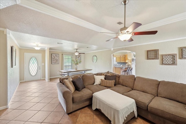 living area with light tile patterned floors, a textured ceiling, crown molding, arched walkways, and a ceiling fan
