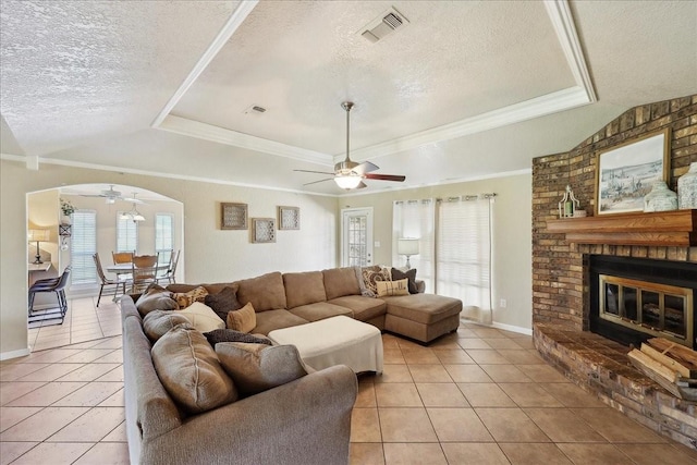 living room featuring light tile patterned flooring, ceiling fan, a raised ceiling, and a textured ceiling