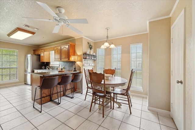 dining space featuring crown molding, a textured ceiling, light tile patterned floors, and baseboards