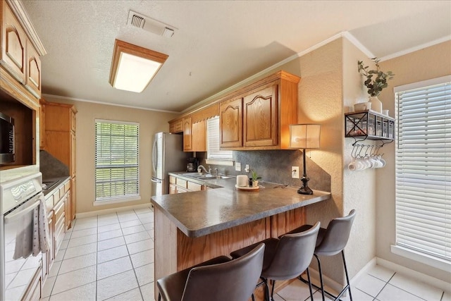 kitchen featuring visible vents, baseboards, white oven, and a sink