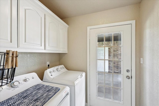 washroom featuring cabinet space, washer and dryer, and a textured wall