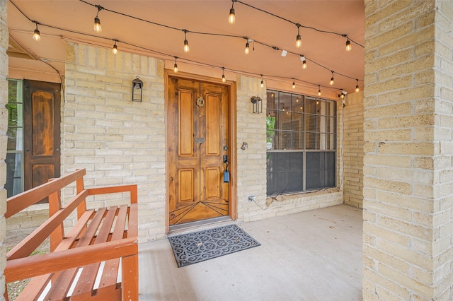 view of exterior entry featuring a porch and brick siding