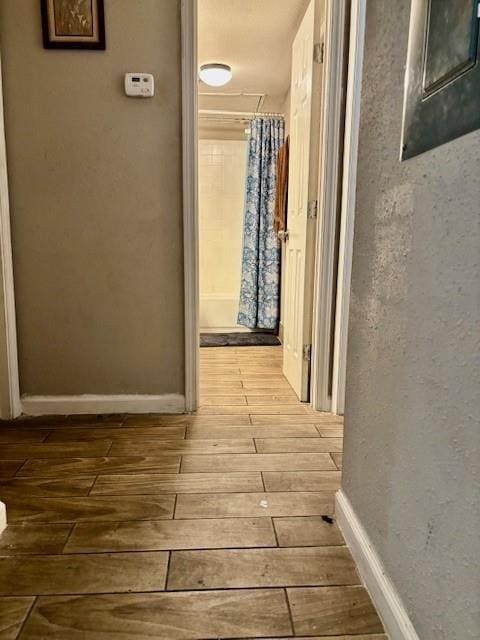 hallway featuring baseboards and wood-type flooring