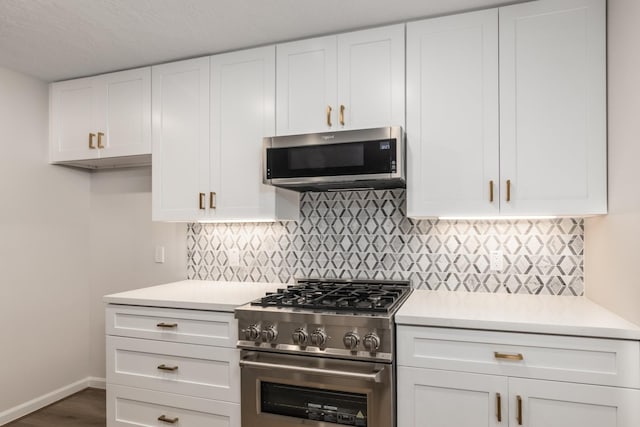 kitchen featuring appliances with stainless steel finishes, white cabinetry, light countertops, and backsplash