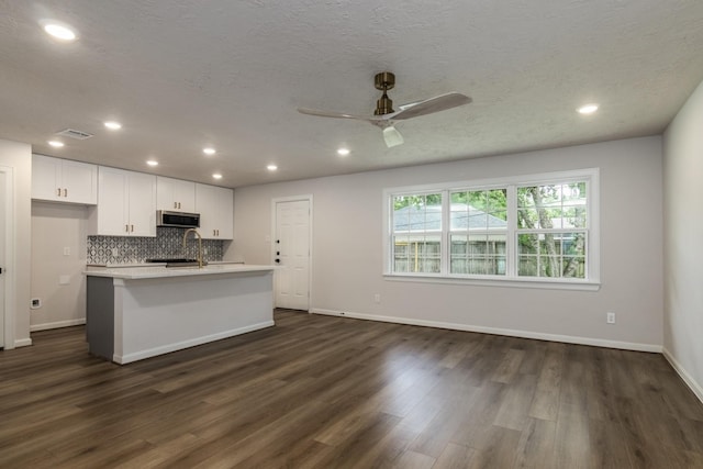 kitchen with stainless steel microwave, light countertops, dark wood-style flooring, white cabinetry, and a ceiling fan