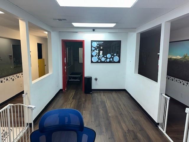 corridor featuring wood finished floors, visible vents, and baseboards