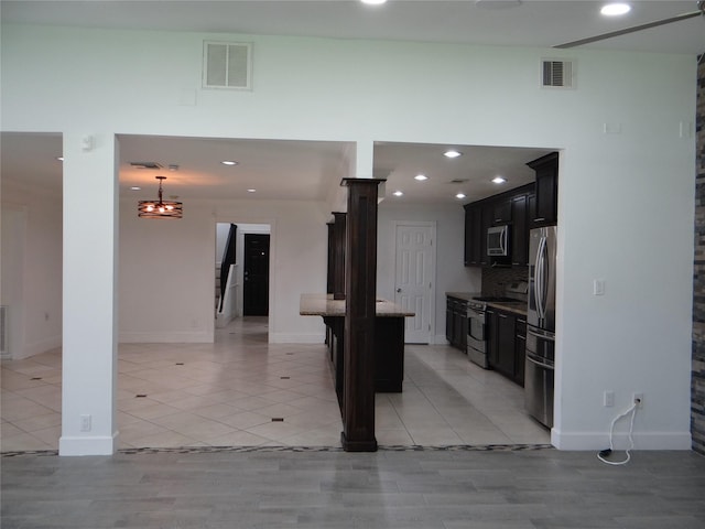 kitchen with visible vents, stainless steel appliances, decorative backsplash, and dark cabinets