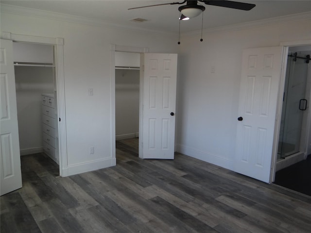 unfurnished bedroom featuring a spacious closet, ornamental molding, and wood finished floors