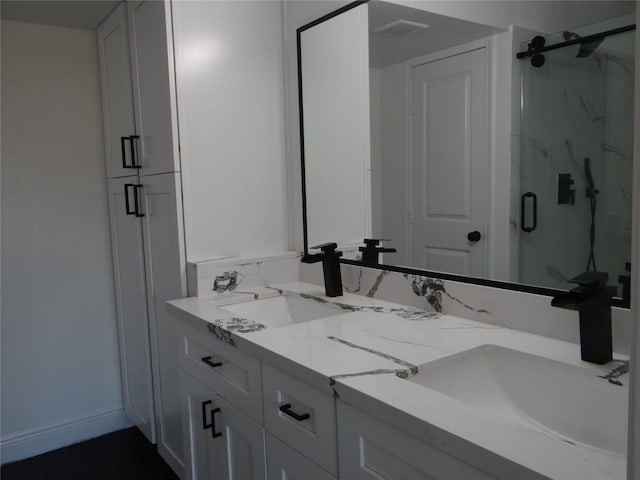 bathroom with visible vents, a marble finish shower, double vanity, and a sink