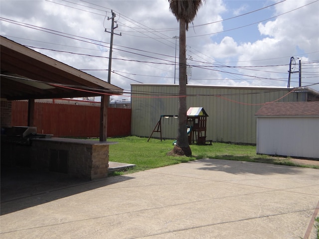 view of patio with a grill, fence, a shed, and an outbuilding