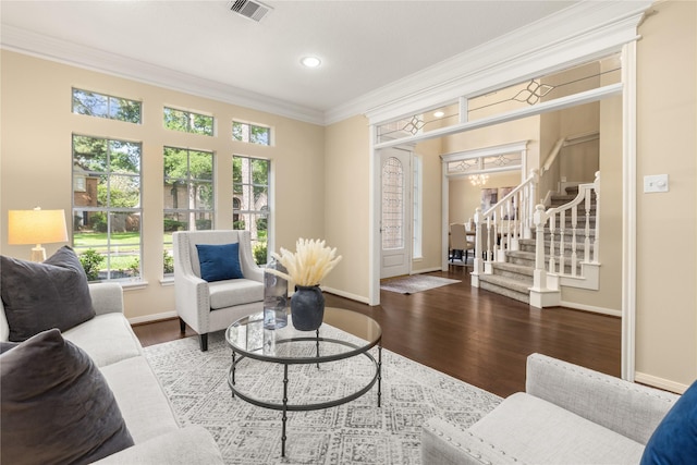 living area with baseboards, visible vents, crown molding, and plenty of natural light
