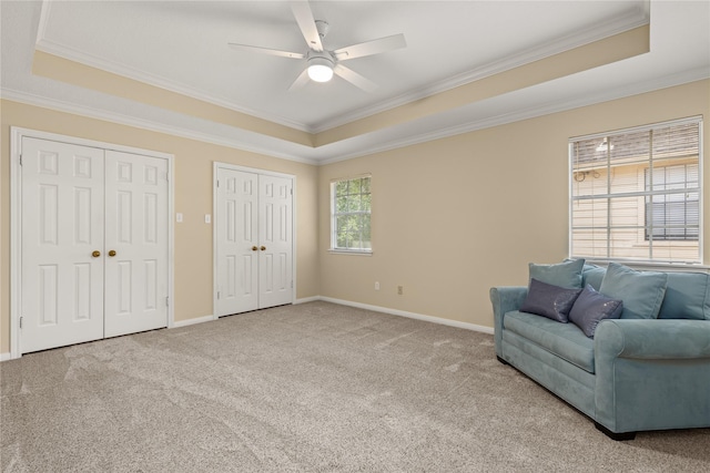 sitting room featuring ornamental molding, carpet flooring, baseboards, a ceiling fan, and a tray ceiling