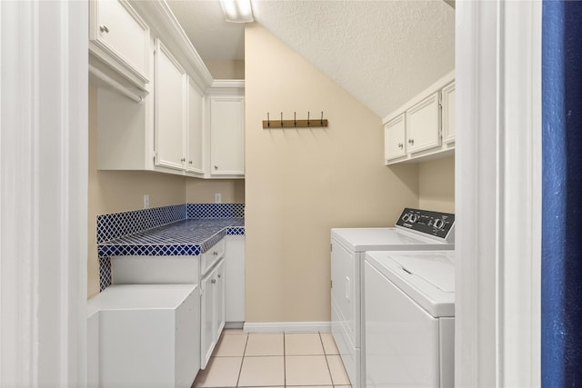 laundry area with cabinet space, independent washer and dryer, light tile patterned flooring, baseboards, and a textured ceiling
