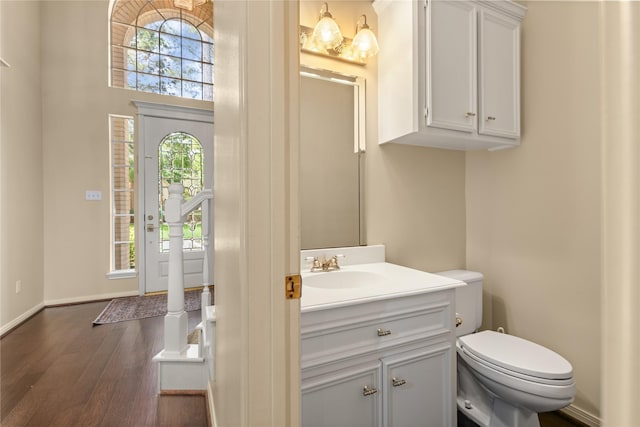 bathroom featuring a wealth of natural light, wood finished floors, toilet, and vanity