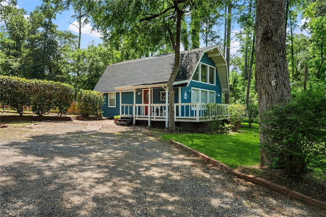 view of front of house with a front yard, board and batten siding, a gambrel roof, and a shingled roof