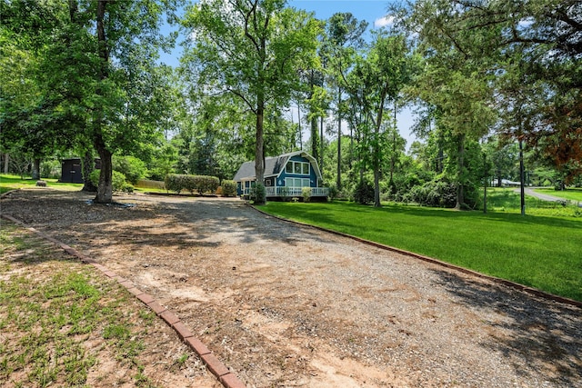 view of front facade with driveway, a gambrel roof, and a front lawn