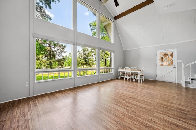 interior space featuring beamed ceiling, high vaulted ceiling, wood finished floors, and a healthy amount of sunlight