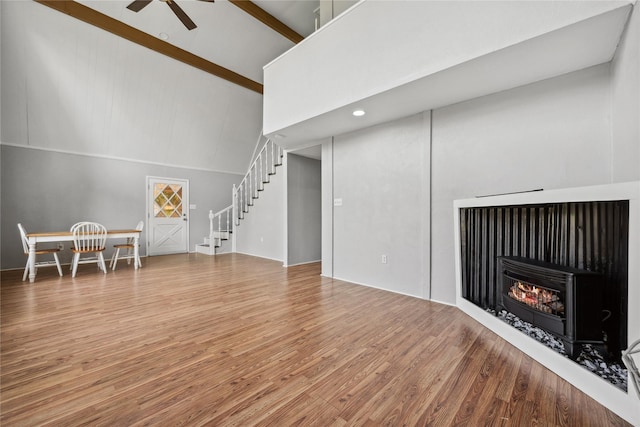 living room with beamed ceiling, stairway, ceiling fan, wood finished floors, and high vaulted ceiling