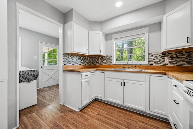 kitchen featuring white cabinetry, a sink, butcher block countertops, light wood finished floors, and backsplash