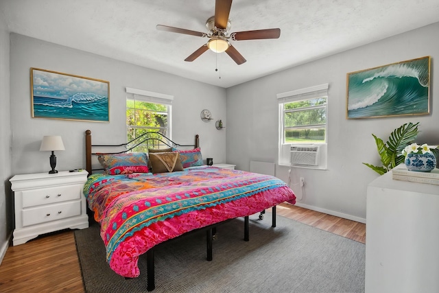 bedroom featuring baseboards, wood finished floors, cooling unit, and ceiling fan