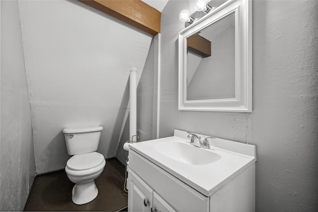 half bath featuring toilet, a textured wall, and vanity