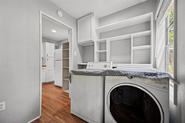 laundry room with cabinet space, wood finished floors, and washer / dryer