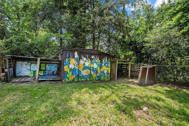 view of yard featuring fence, a storage unit, and an outbuilding