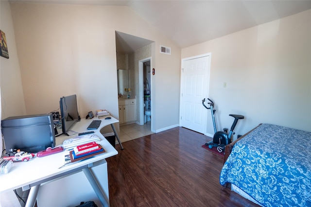 bedroom featuring wood finished floors, ensuite bathroom, baseboards, visible vents, and lofted ceiling