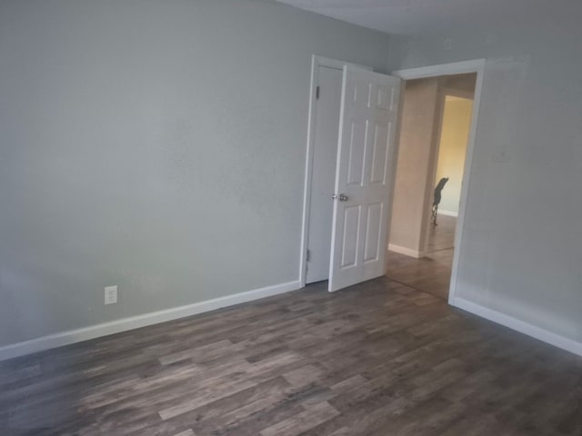 spare room with dark wood-type flooring and baseboards
