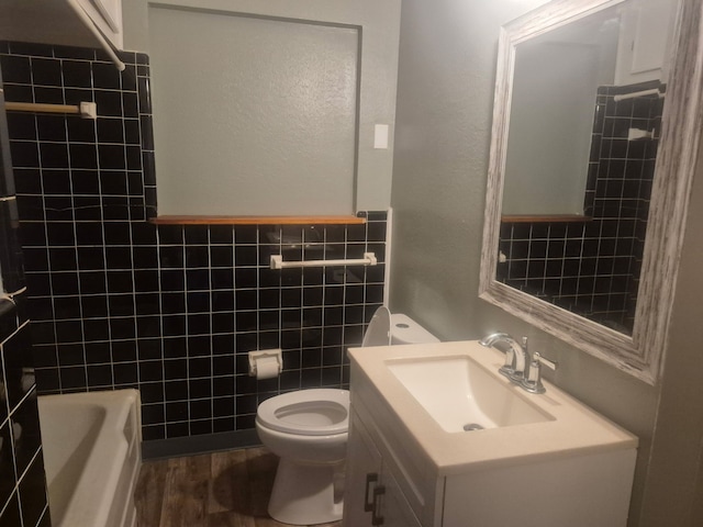 bathroom with tile walls, vanity, toilet, shower / washtub combination, and wood finished floors