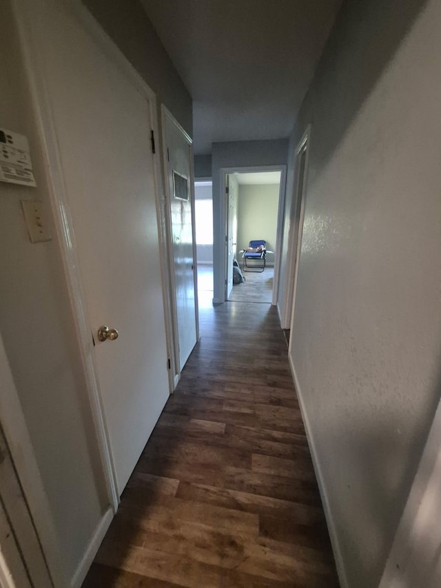 corridor featuring baseboards and dark wood-style flooring