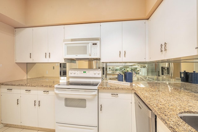 kitchen featuring light stone counters, white appliances, and white cabinets