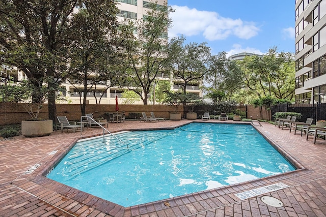 community pool with a patio and fence