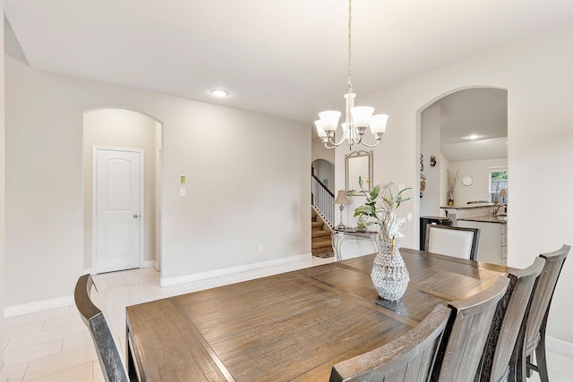 dining room with arched walkways, a notable chandelier, and stairway