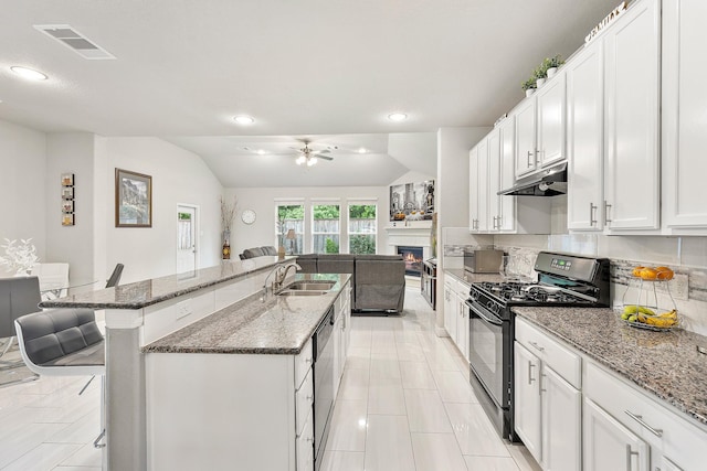 kitchen with under cabinet range hood, a sink, black range with gas stovetop, visible vents, and a kitchen breakfast bar
