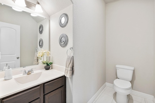 half bath featuring lofted ceiling, baseboards, toilet, tile patterned floors, and vanity